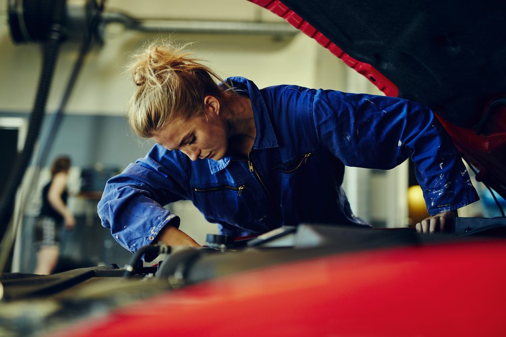 Woman mechanic working on car.
