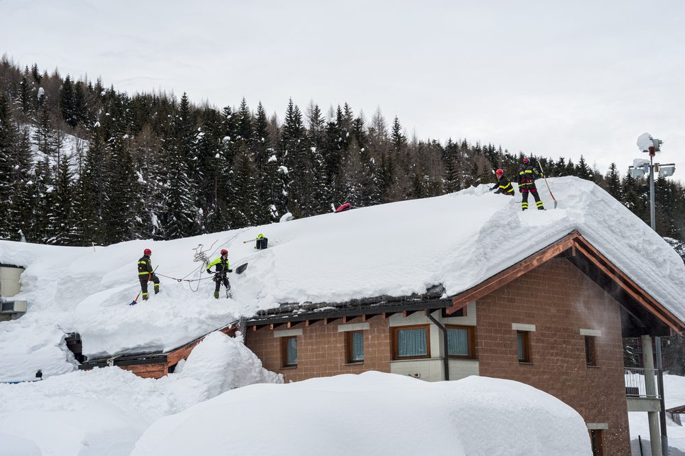 House under heavy snow, with firefighters.