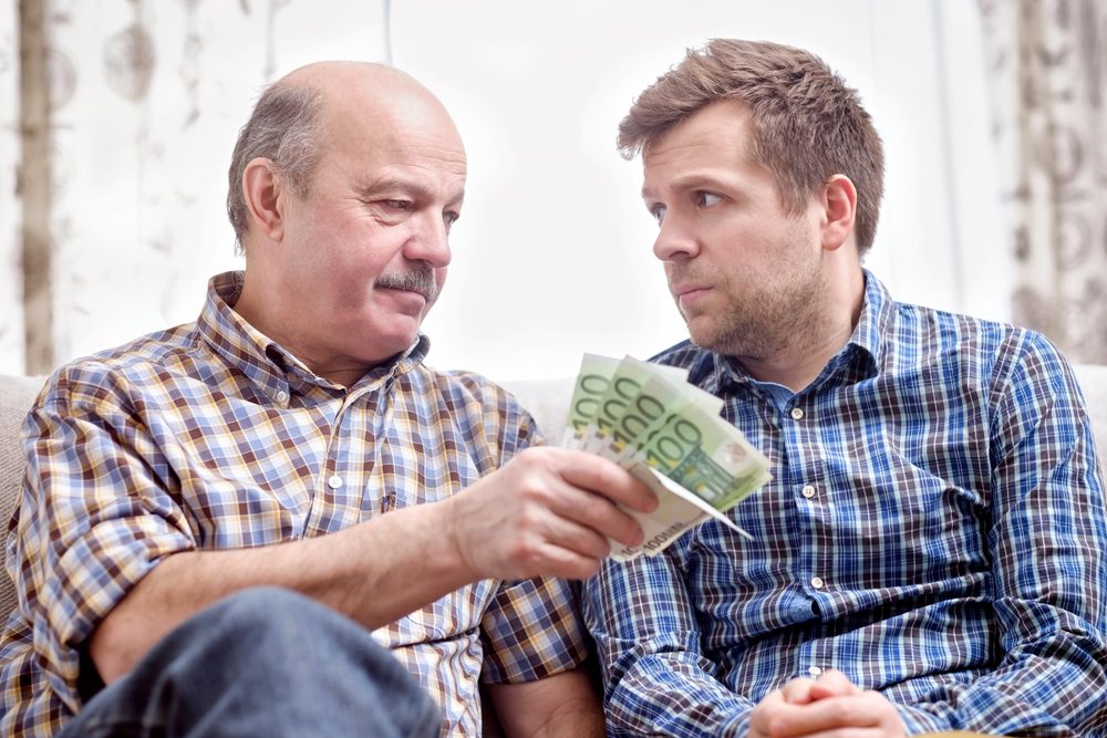 Father giving worried son some money.