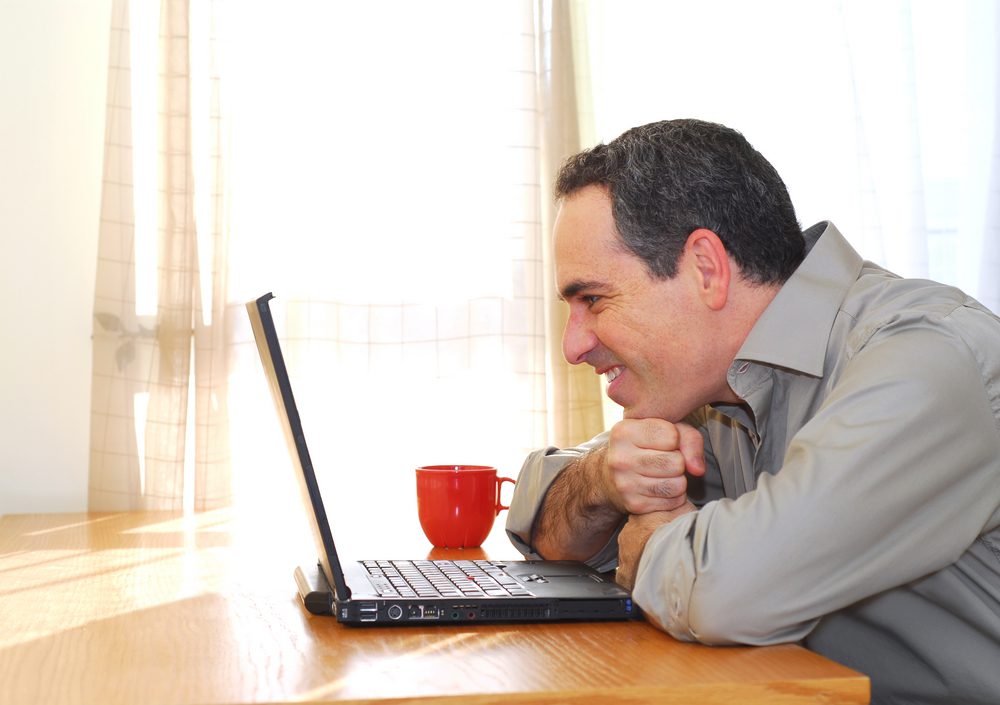 Happy man looking at laptop.