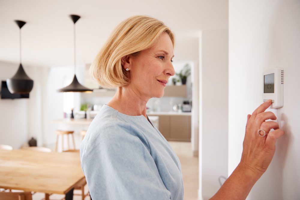 Woman using thermostat.