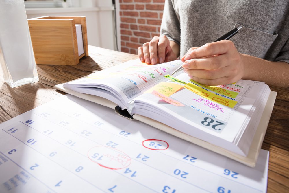 Woman marking down date on a calendar and agenda.