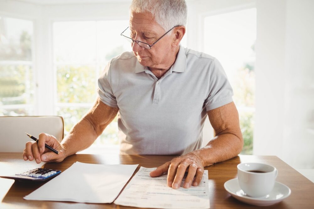 Worried senior man with tax documents at home