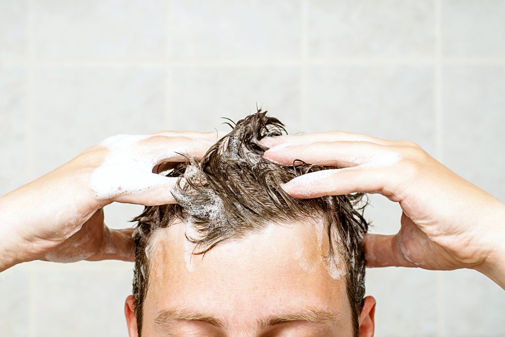 Young man washing his hair.