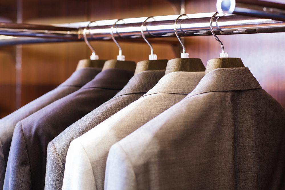 Men's suit jacket hanging in wardrobe.
